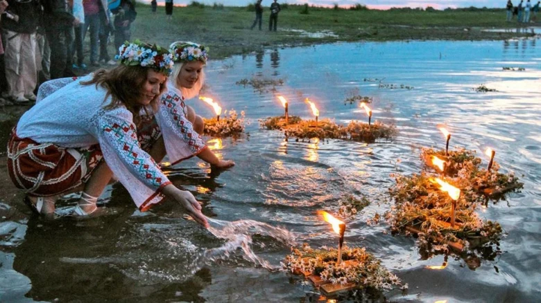 Дівчата в народних костюмах запалюють свічки на Івана Купали