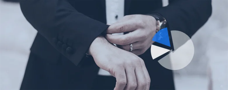Чоловік у смокінгу регулює годинник на руці.